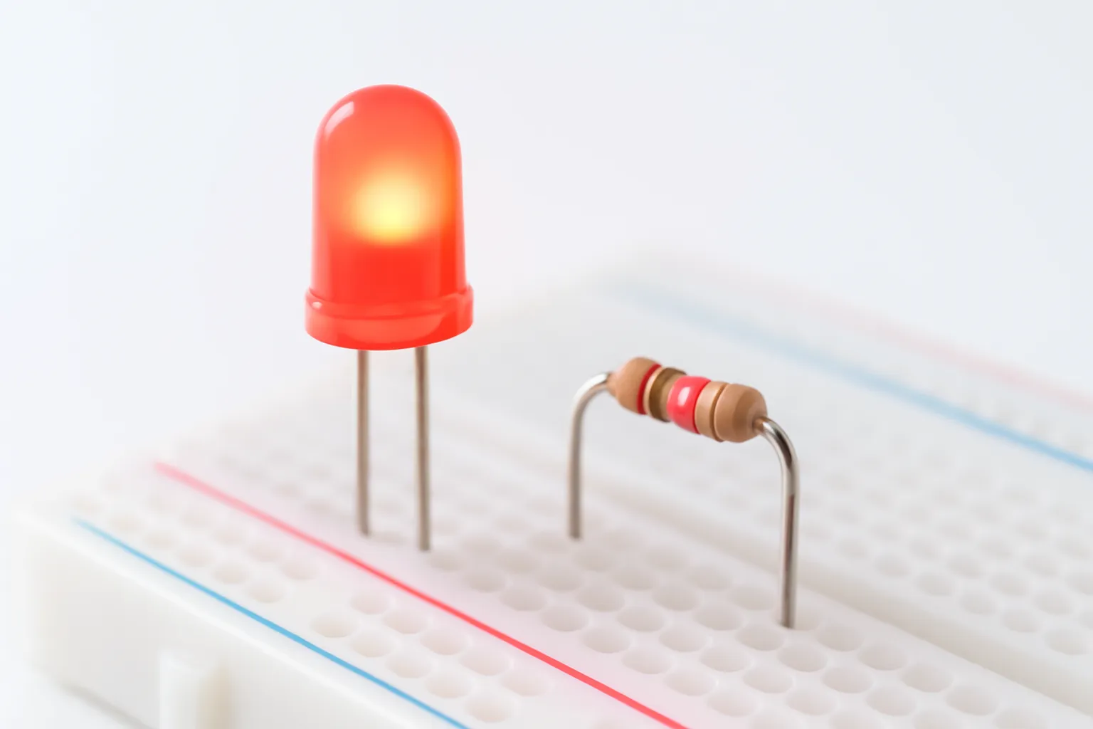 Đèn LED đỏ sáng trên bảng cắm thử cạnh một điện trở
